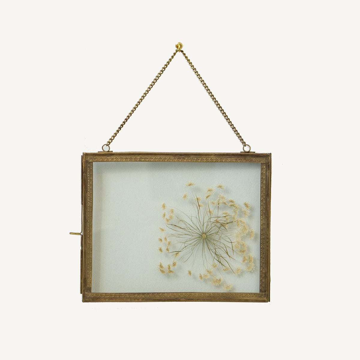 Decorative frame with dried flowers inside, hanging on a white background
