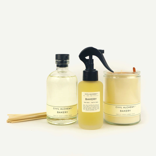 Three products from Civil Alchemy on a white background: a bottle, a spray bottle, and a candle.