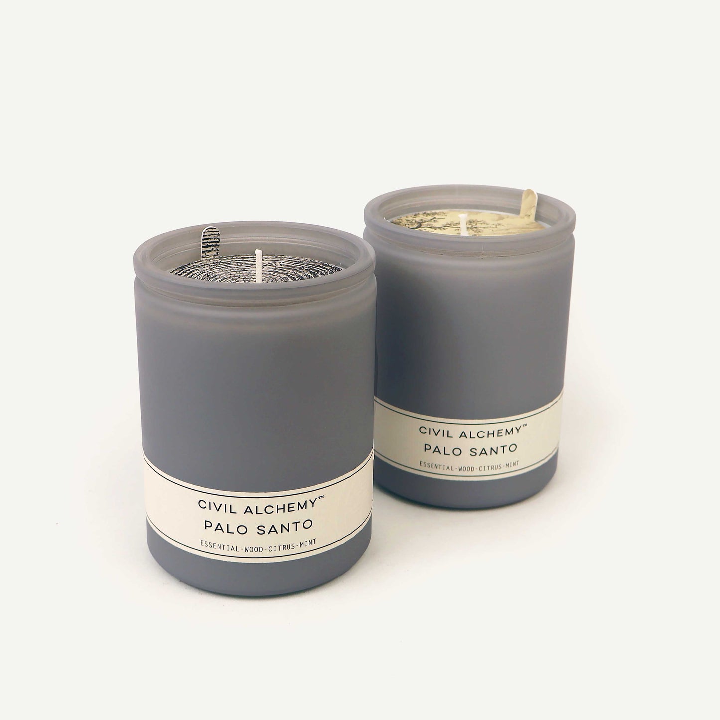 Two gray candles with labels on a white background
