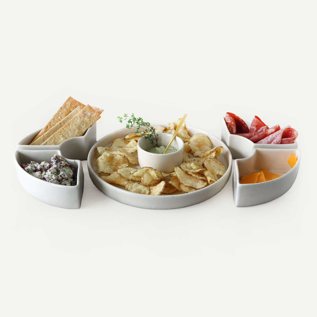 White ceramic platter with compartments filled with snacks on a white background