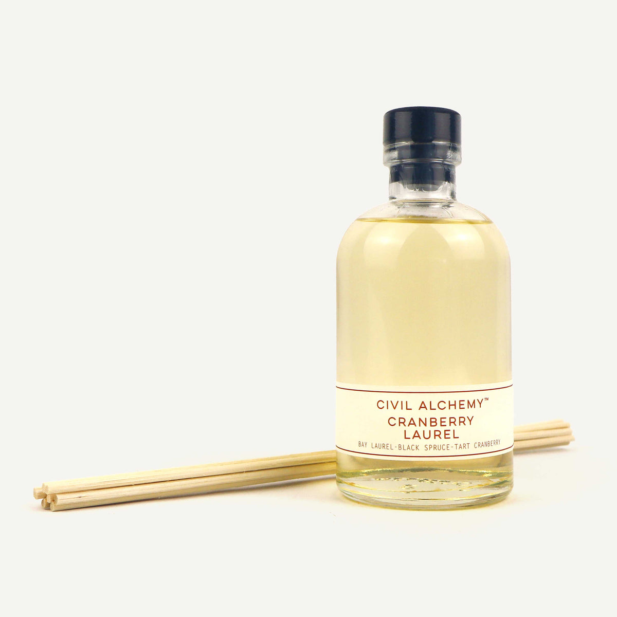Bottle of Civil Alchemy Cranberry Laurel diffuser with reeds on a white background