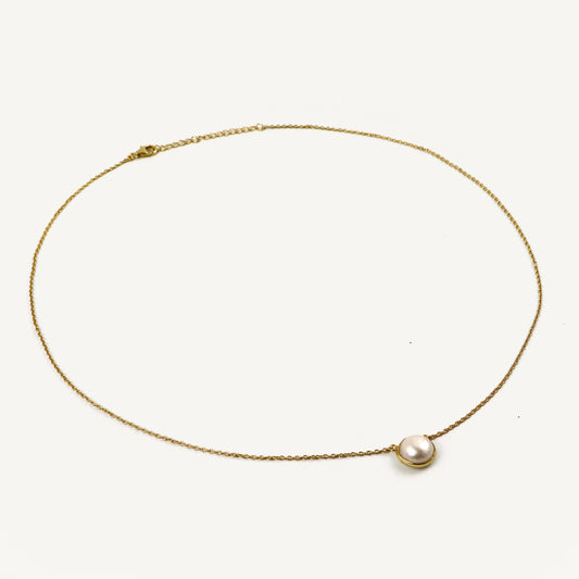 Gold necklace with a single pearl on a white background