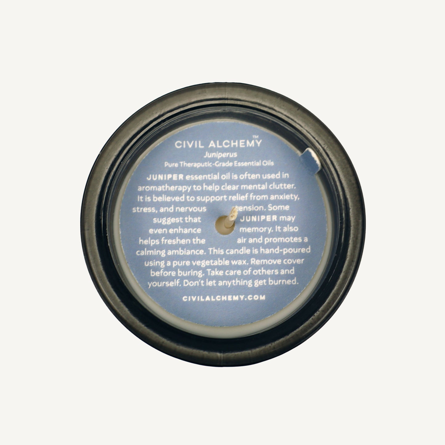 Candle lid with text about Juniper essential oil and Civil Alchemy branding on a white background