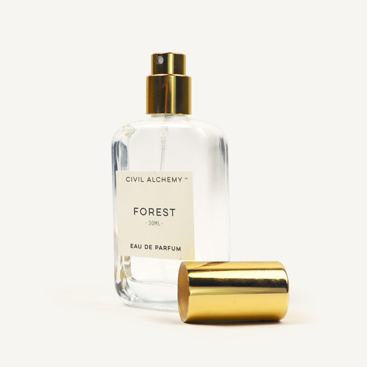 Clear perfume bottle with gold cap labeled 'Forest' by Civil Alchemy on a white background