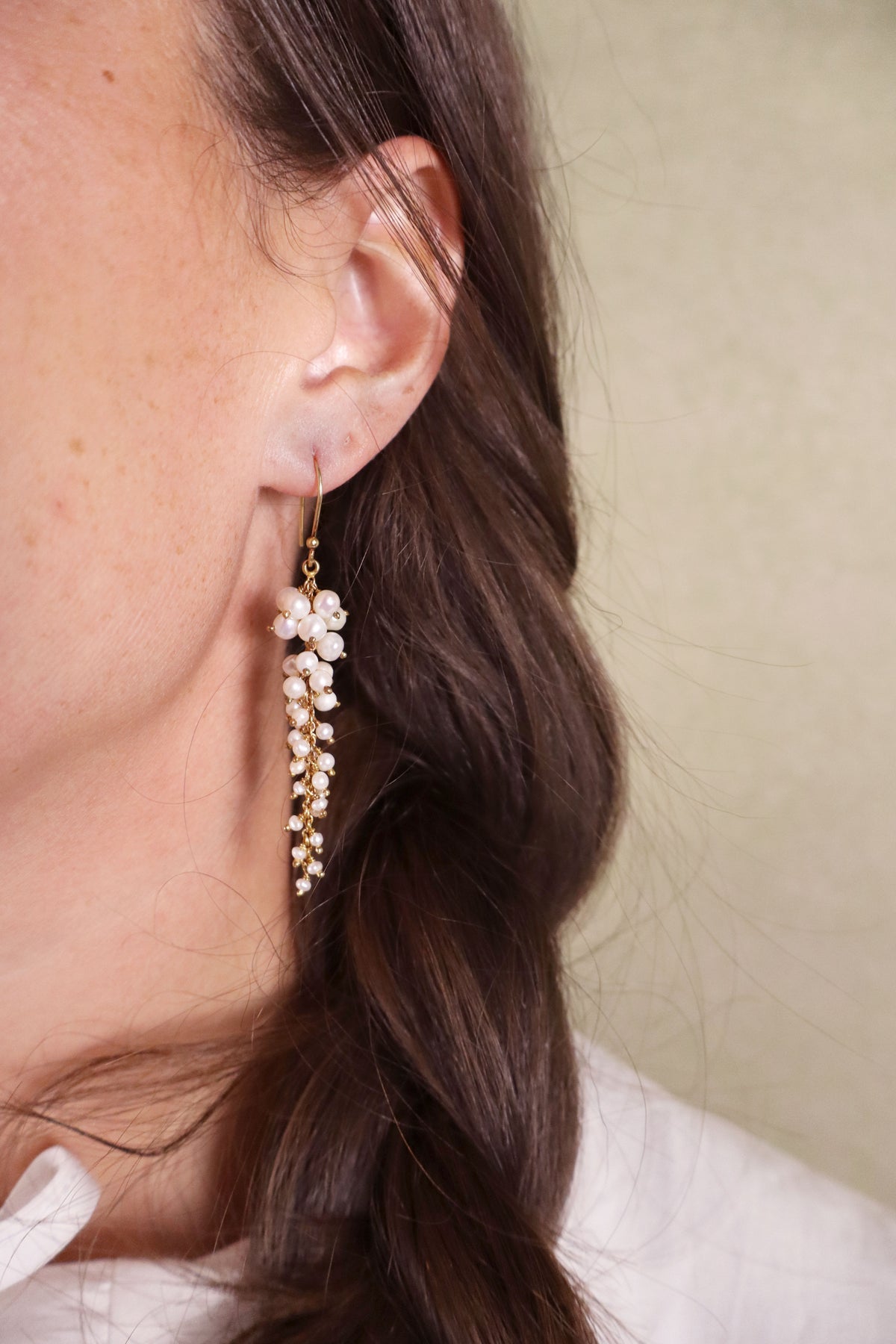 Close-up of a person wearing a floral earring with a neutral background