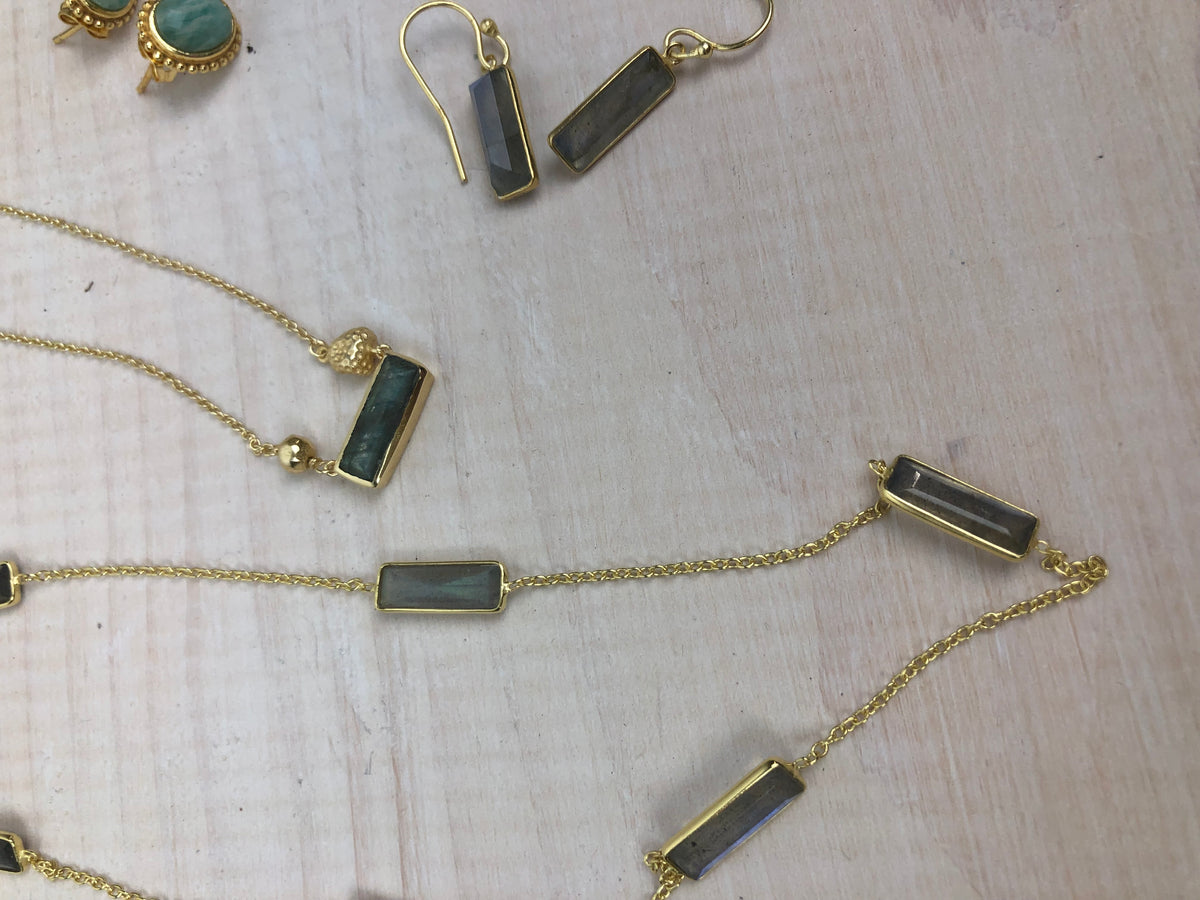 Gold necklaces and earrings with black stones on a light wooden surface