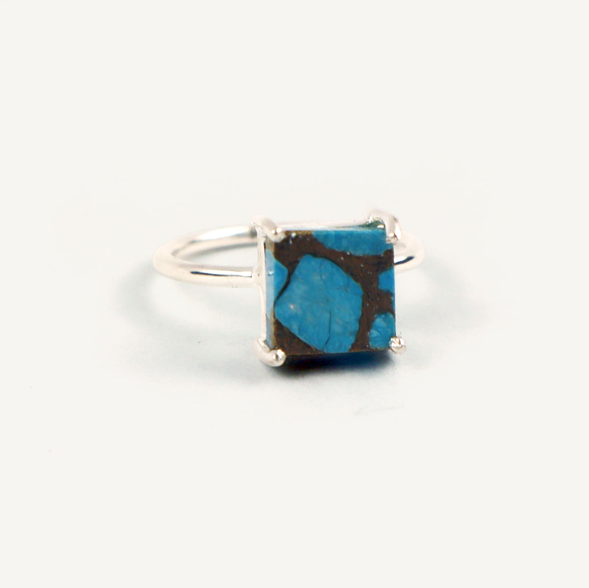Silver ring with a square blue stone on a white background