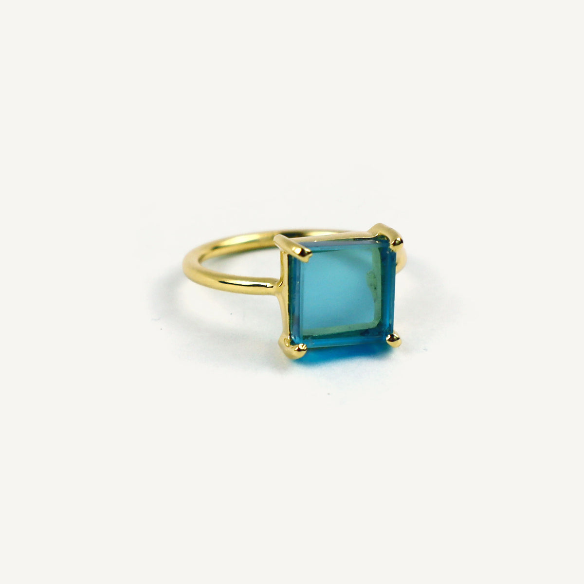 Gold ring with a square blue gemstone on a white background
