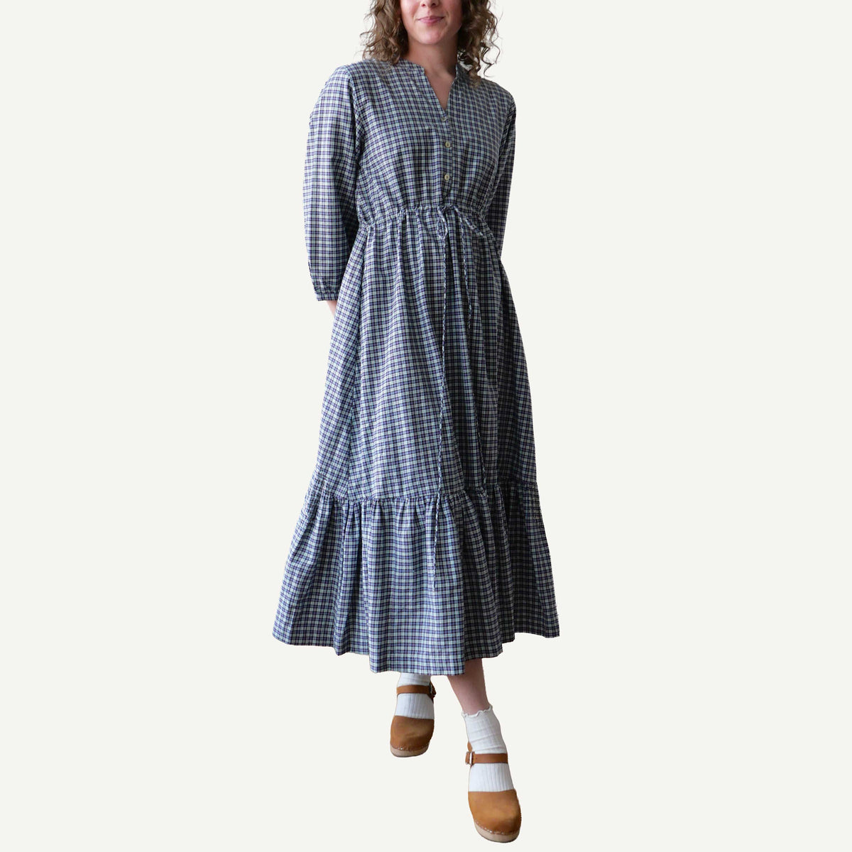 Woman wearing a blue and white checkered dress on a plain background