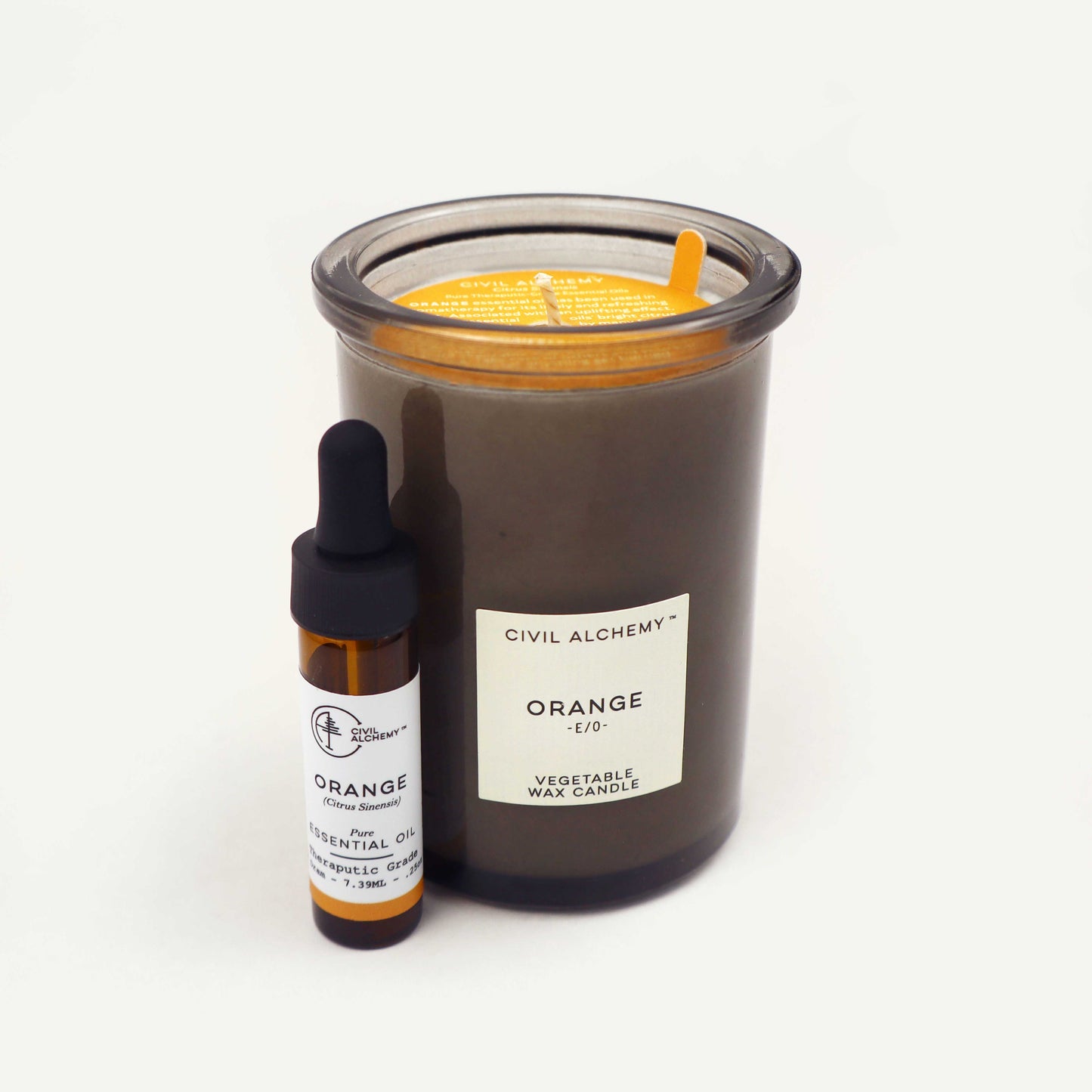Candle and essential oil bottle with 'Civil Alchemy' branding on a white background