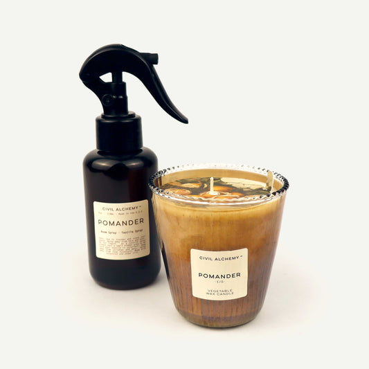 Brown spray bottle and glass candle with 'Civil Alchemy Pomander' label on a white background