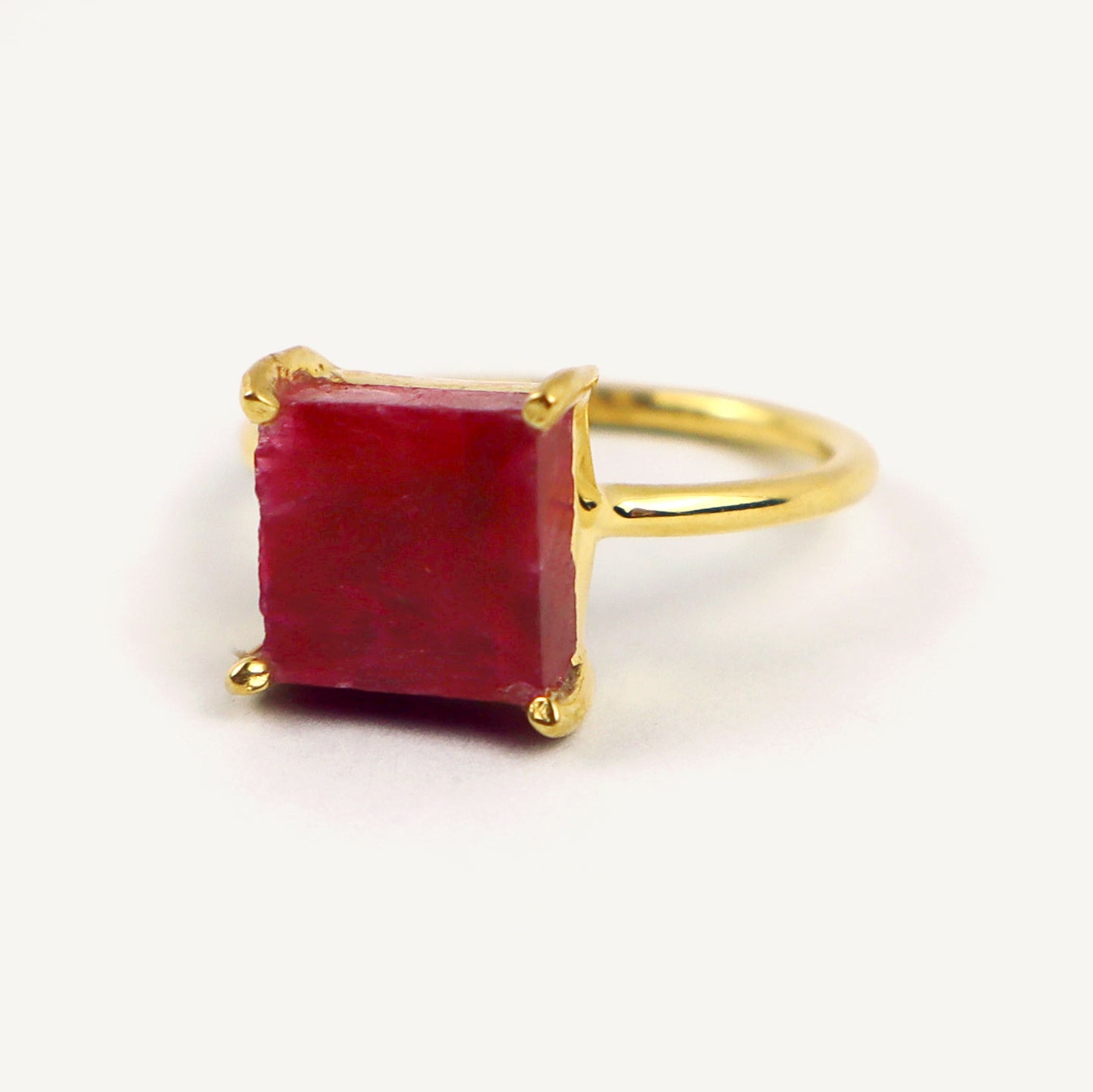 Gold ring with a red gemstone on a white background