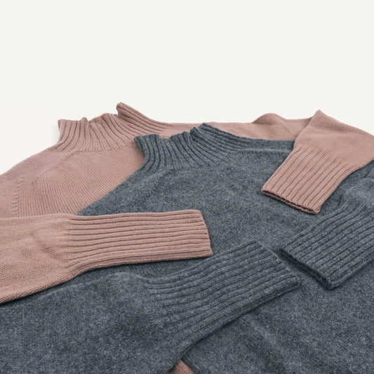 Two sweaters, one beige and one gray, on a light background