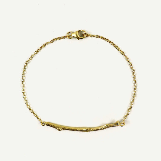 Gold bracelet with a branch-like design on a white background