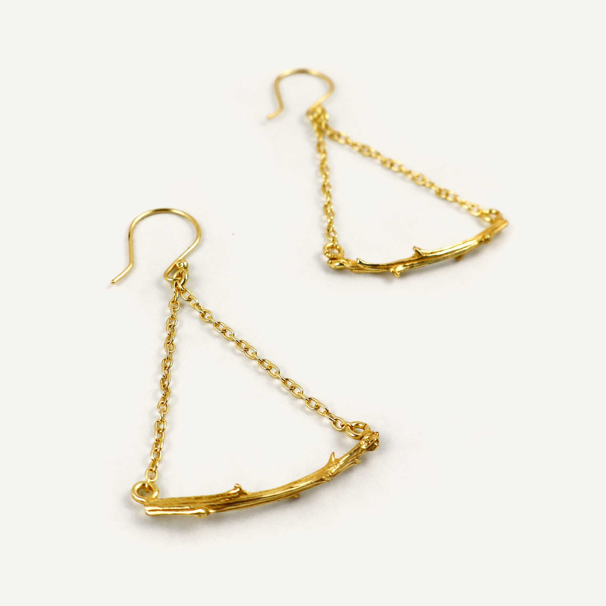 Gold branch-like earrings on a white background