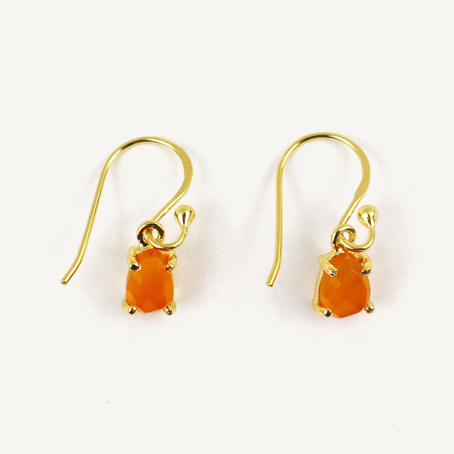 Gold earrings with carnelian gemstones on a white background