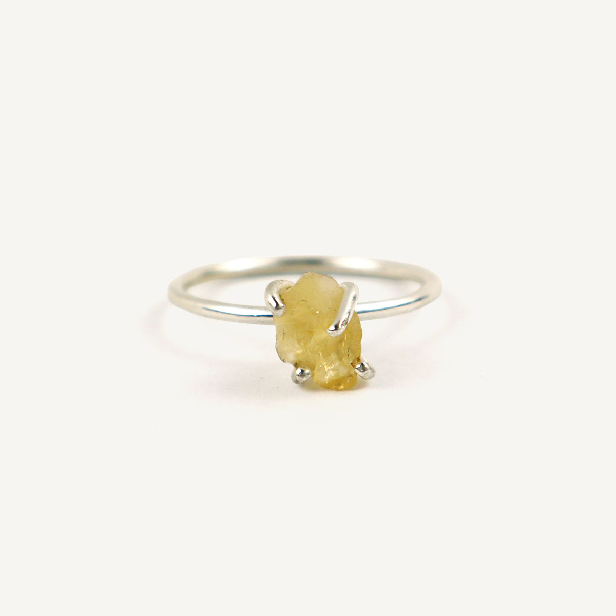 Silver ring with a yellow gemstone on a white background