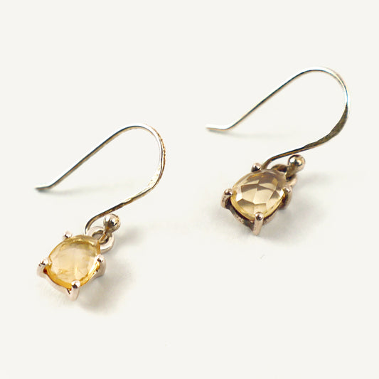 Silver earrings with yellow gemstones on a white background