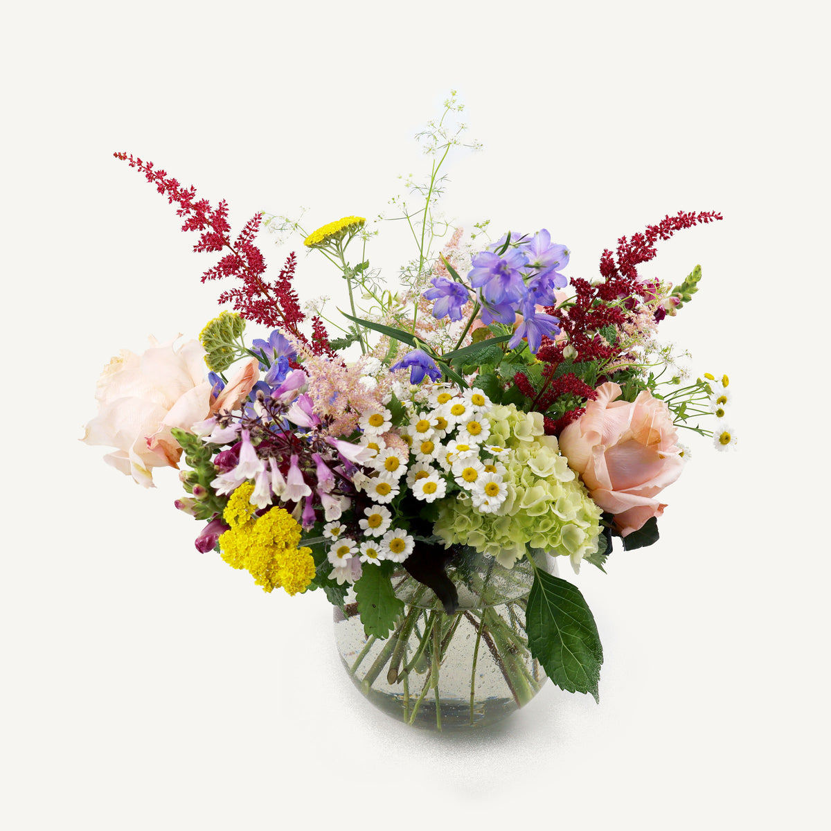 Bouquet of colorful flowers in a clear vase on a white background