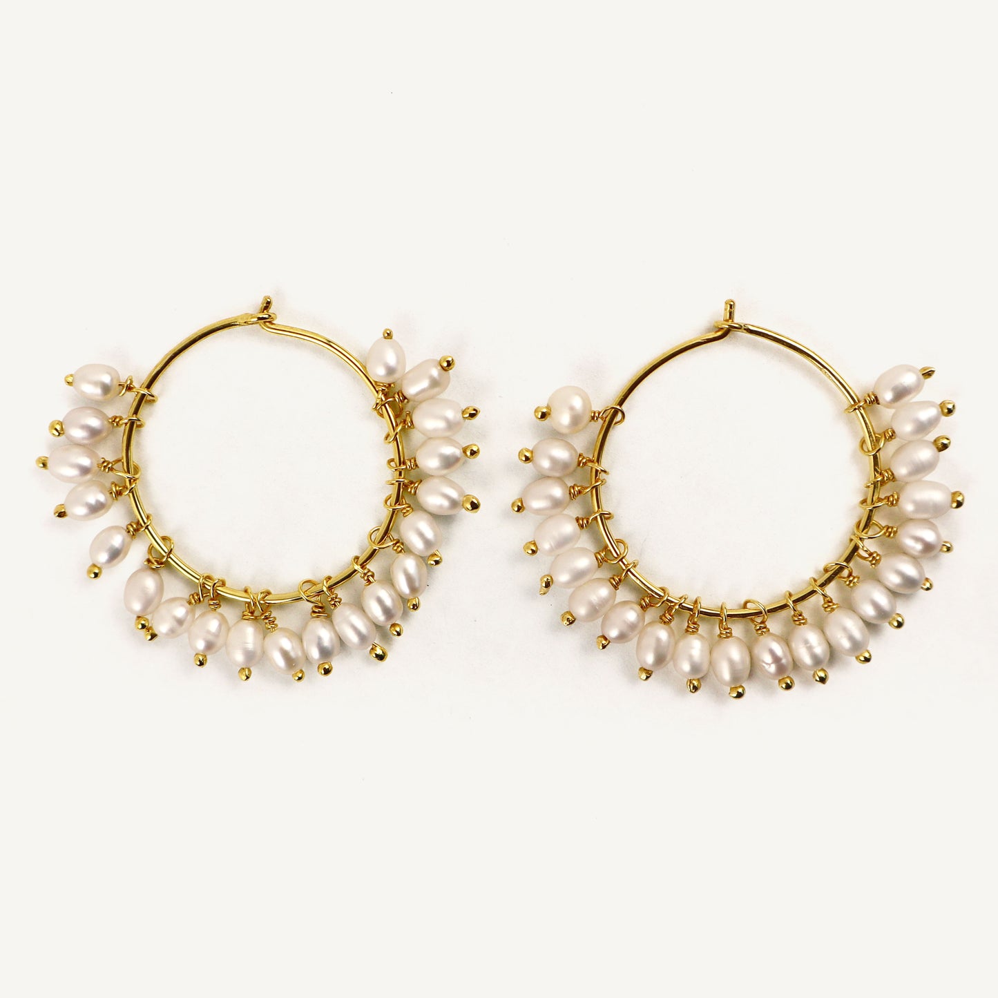 Gold hoop earrings with pearl accents on a white background