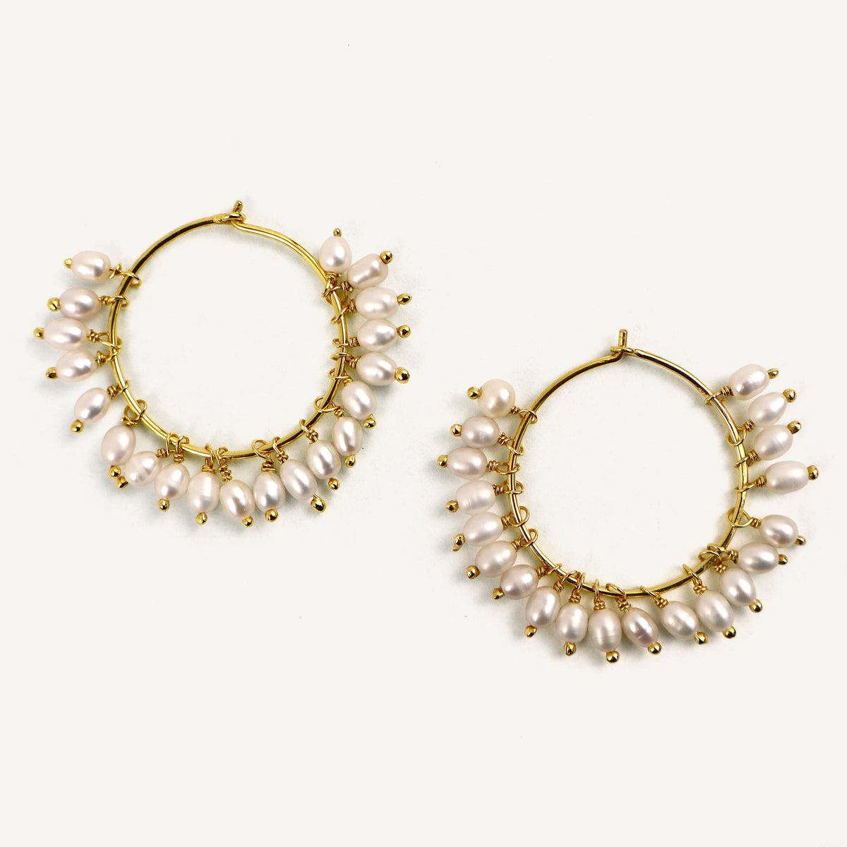 Gold hoop earrings with pearl accents on a white background