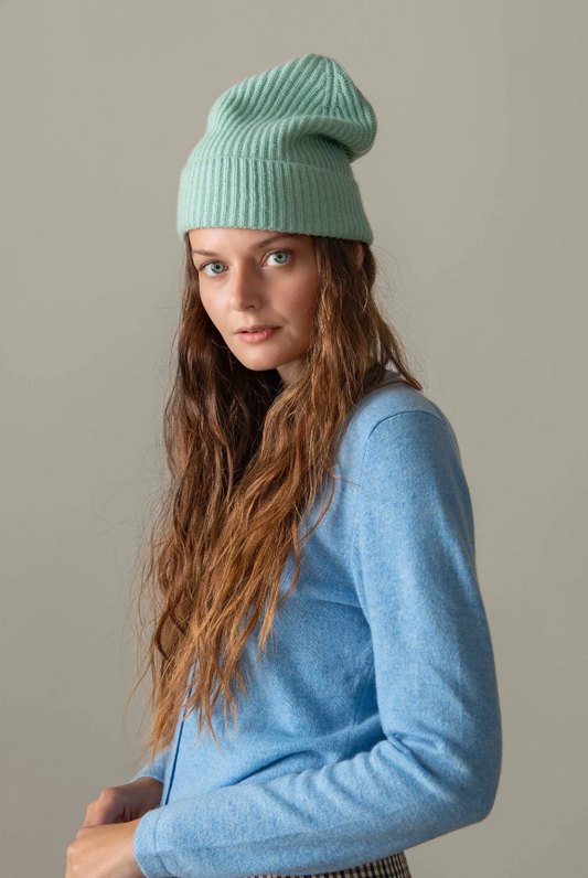 Woman wearing a light blue knit hat and sweater against a plain background