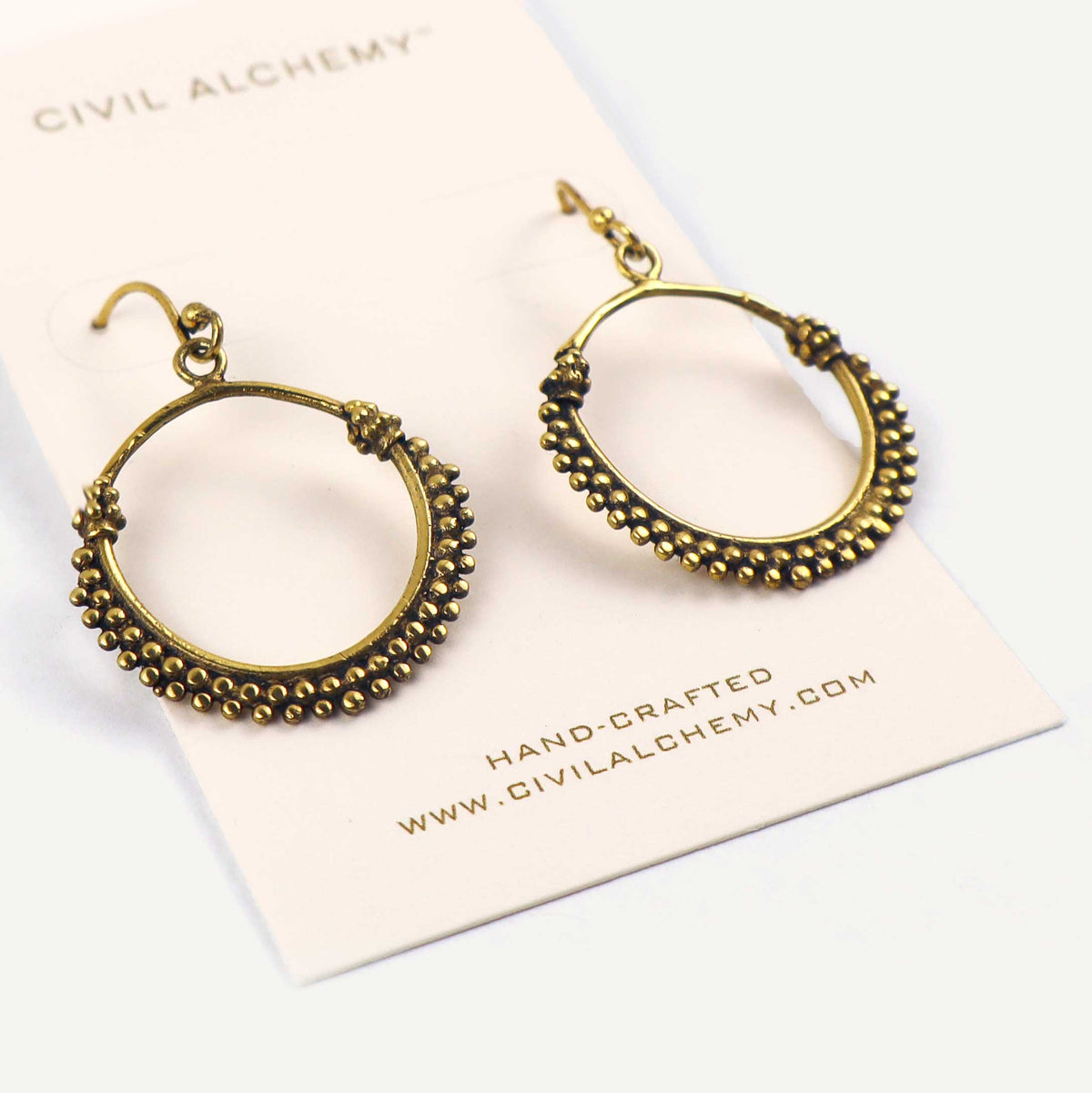 Pair of gold hoop earrings on a Civil Alchemy branded card.