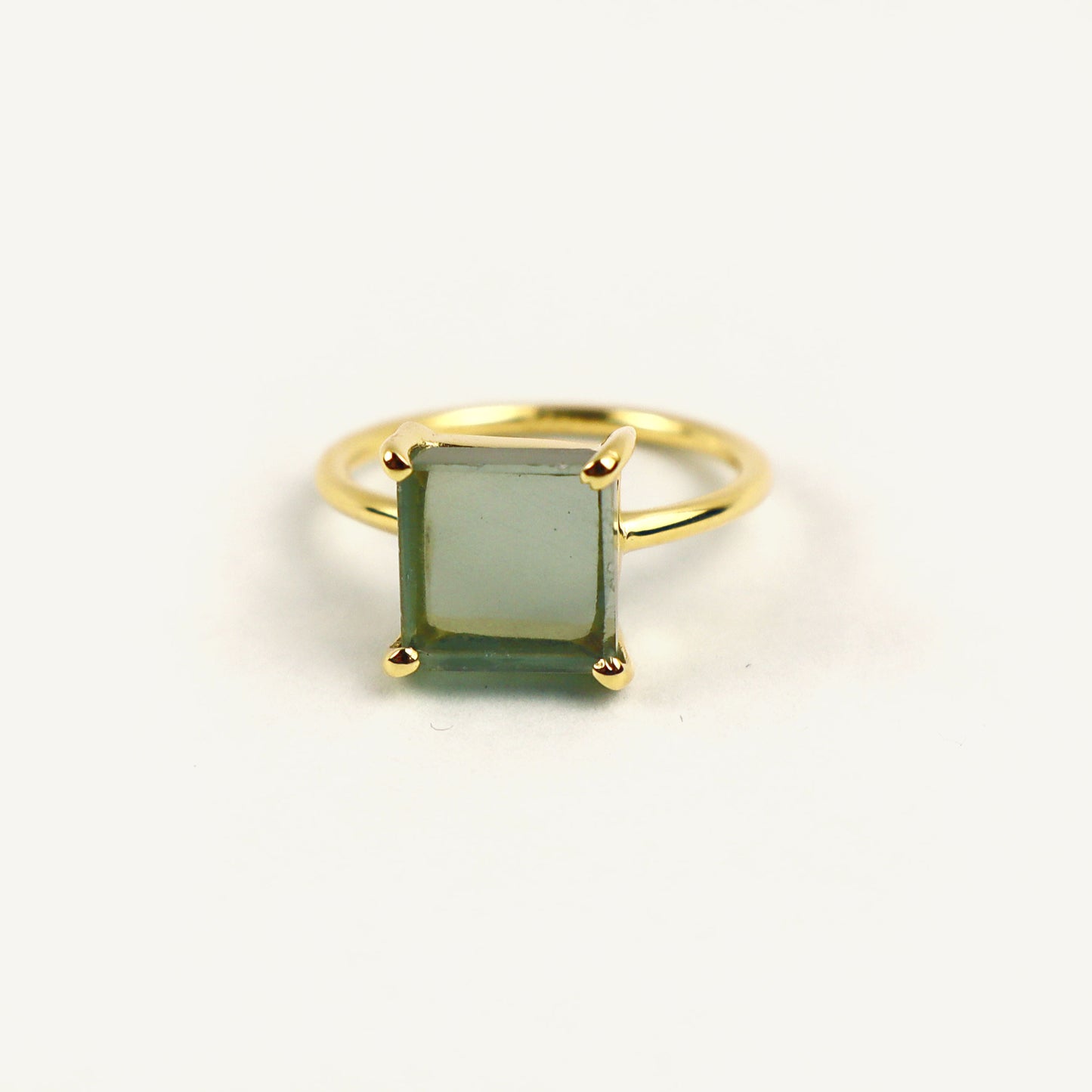 Gold ring with a green gemstone on a white background