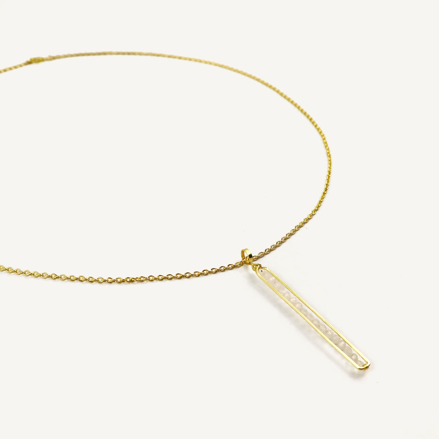 Gold necklace with a bar pendant on a white background