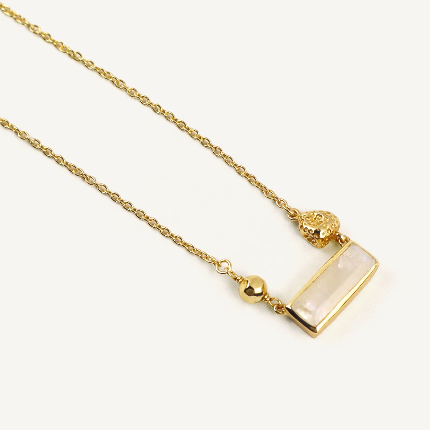 Gold necklace with a rectangular pendant on a white background