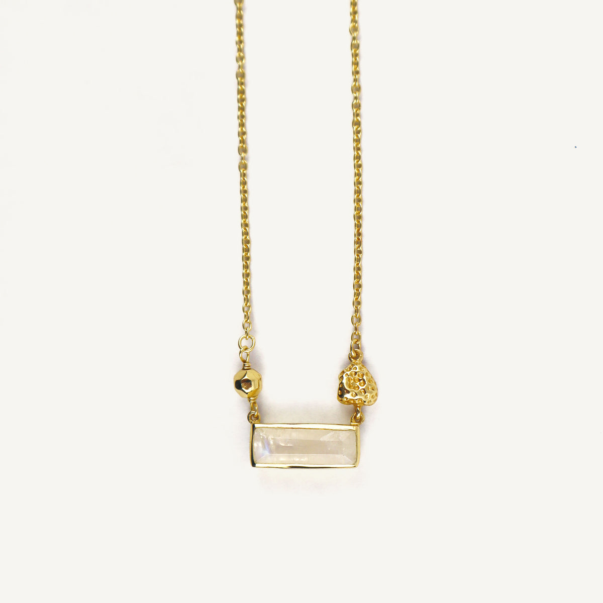 Gold necklace with a rectangular pendant on a white background