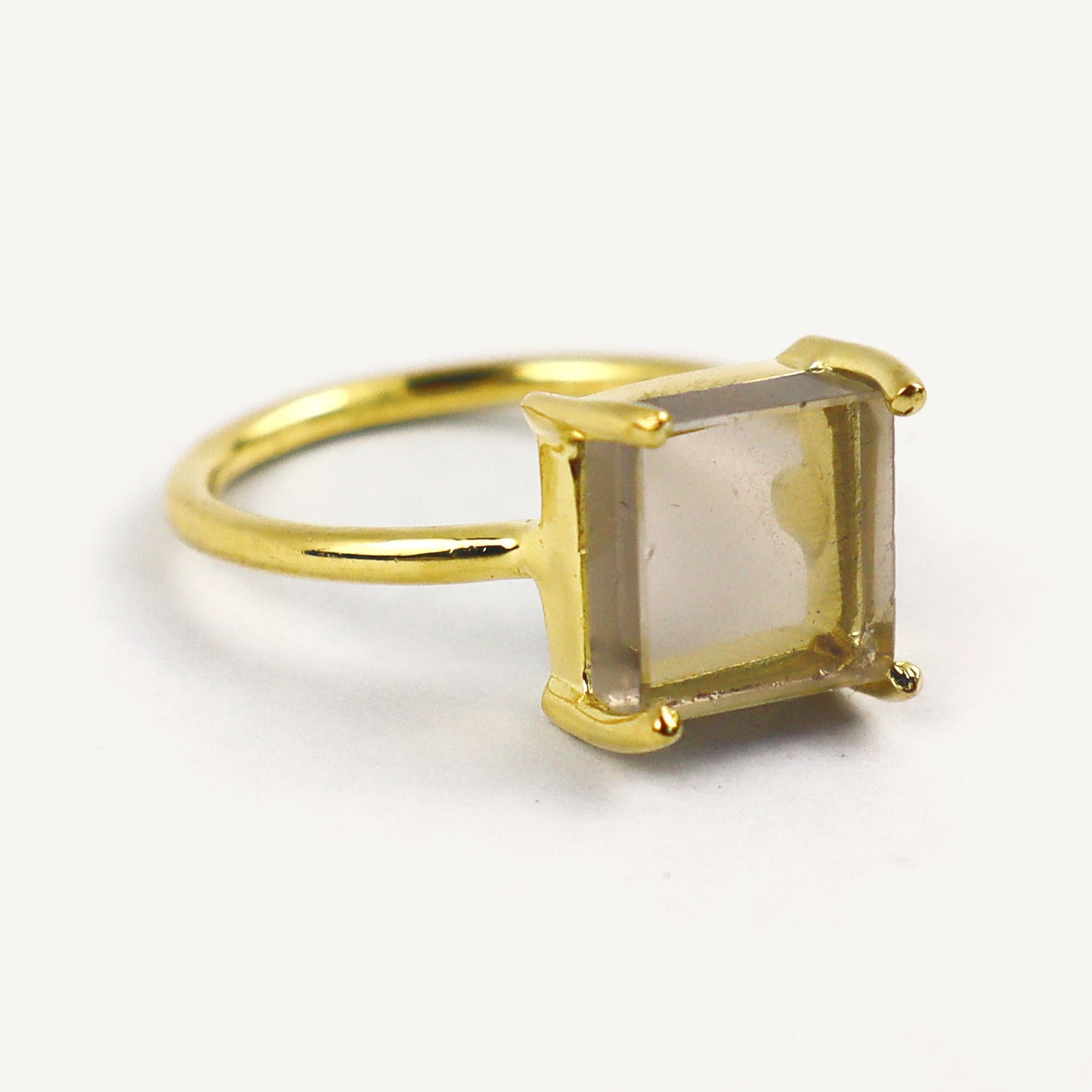 Gold ring with a square-cut gemstone on a white background