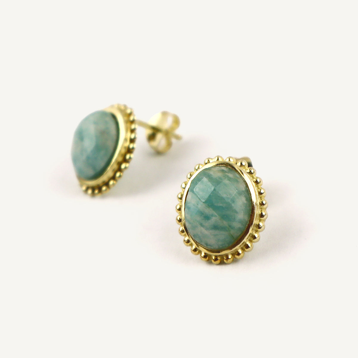 Gold-framed earrings with green gemstones on a white background