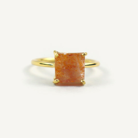 Gold ring with a square-cut orange gemstone on a white background