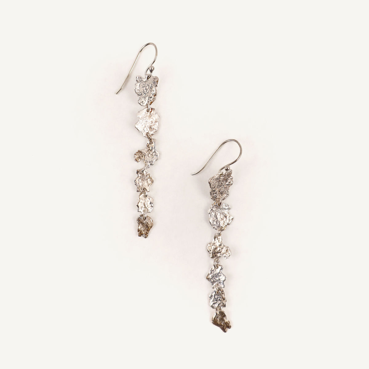 Pair of silver floral earrings on a light beige background