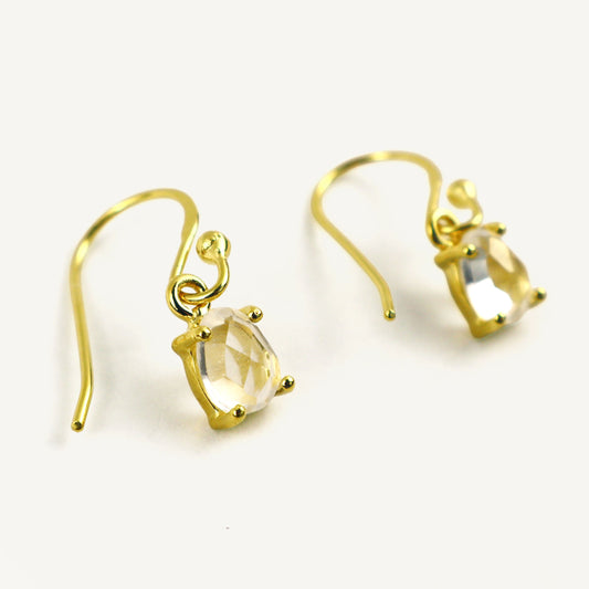 Gold earrings with clear gemstones on a white background