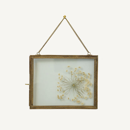 Decorative frame with dried flowers inside, hanging on a white background
