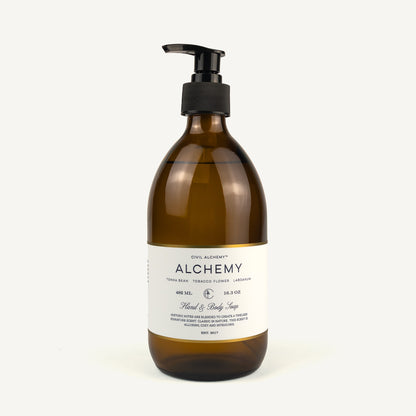 Alchemy Hand & Body Soap in a 450 mL amber glass bottle with a black pump dispenser and a white label, set against a plain off-white background.