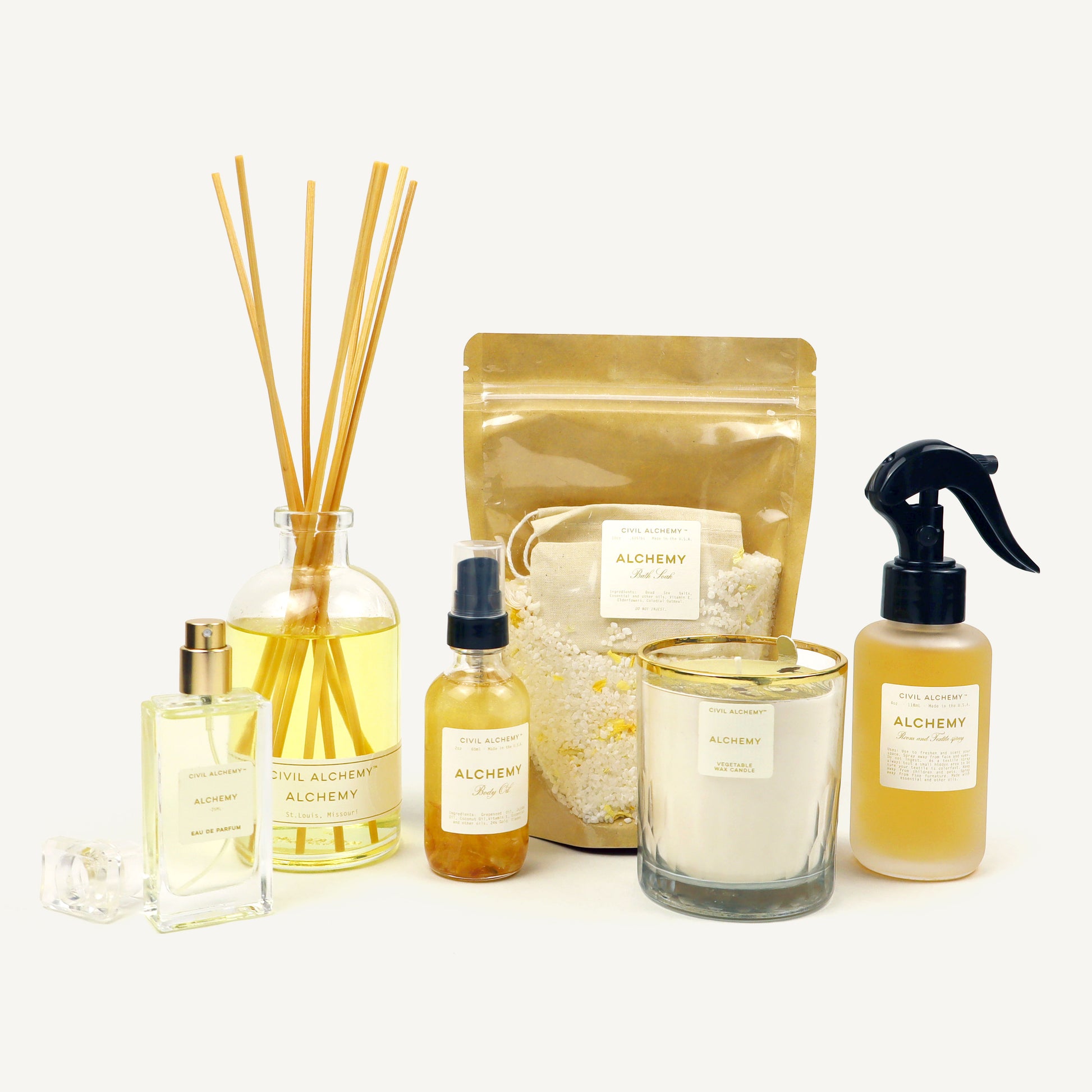 Collection of Alchemy brand products including candles, diffusers, and bottles on a white background