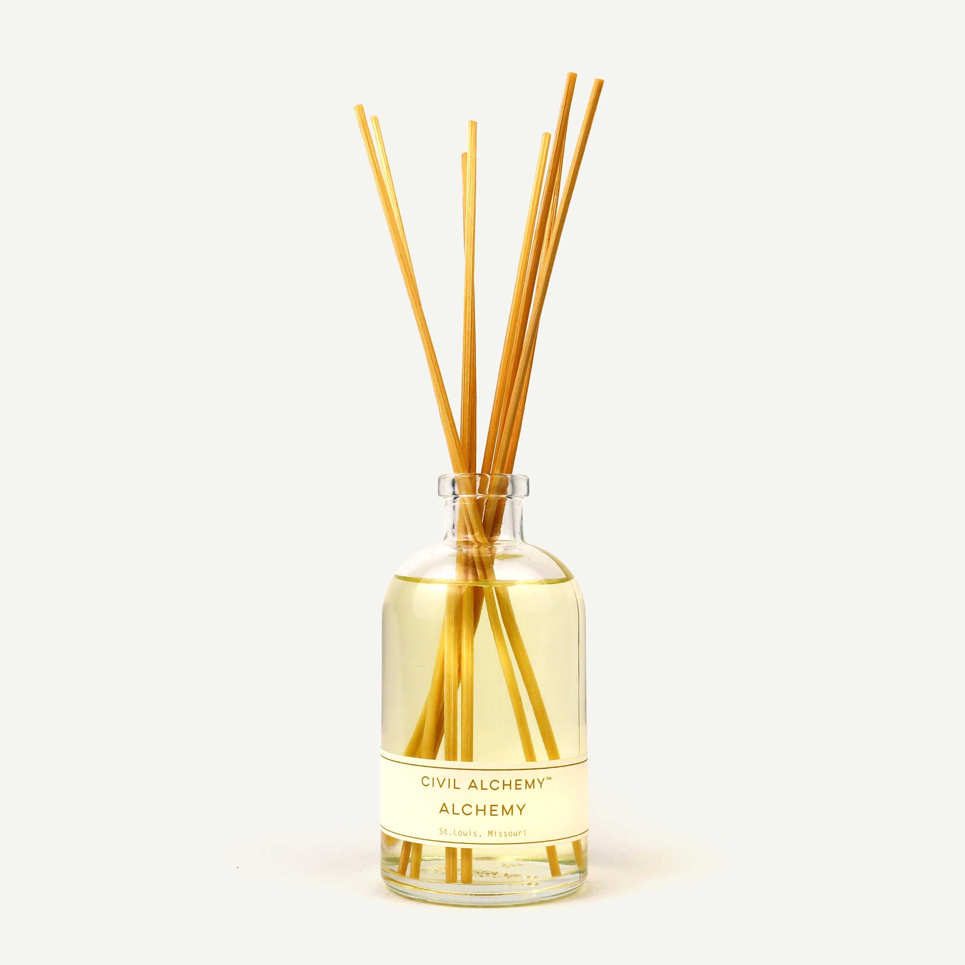 Reed diffuser with sticks in a glass bottle labeled 'Civil Alchemy' on a light background
