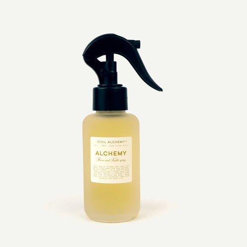 Bottle of 'Alchemy' spray with a black nozzle on a white background