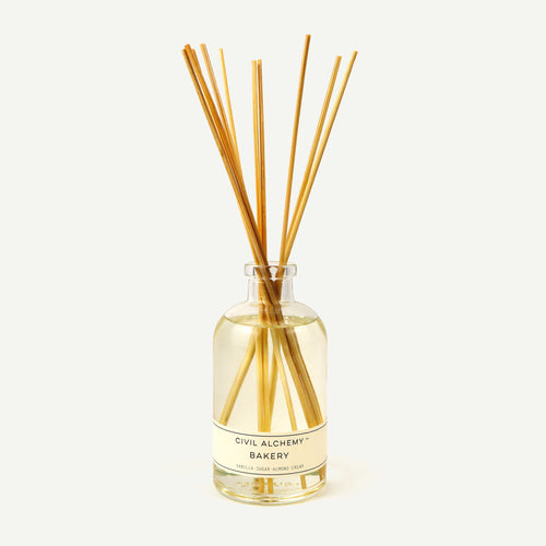 Diffuser bottle with wooden sticks labeled 'Civil Alchemy Bakery' on a white background