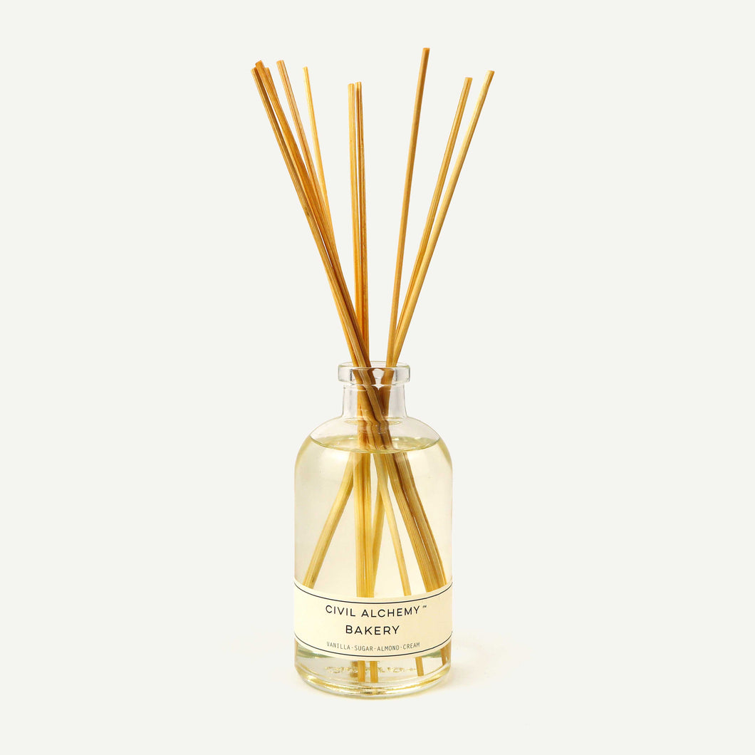 Diffuser bottle with wooden sticks labeled 'Civil Alchemy Bakery' on a white background