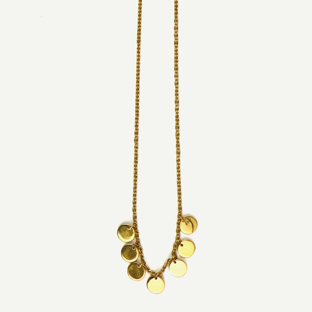 Gold necklace with round pendants on a light beige background
