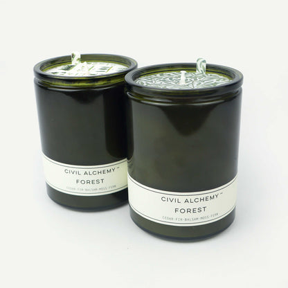 Two green candles labeled 'Civil Alchemy Forest' on a white background