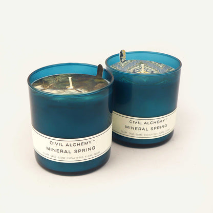 Two blue Civil Alchemy candles with "Mineral Spring" labels on a white background