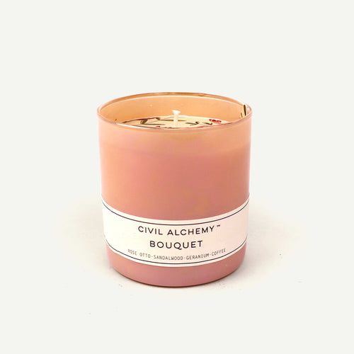 Pink candle with a white label on a light beige background