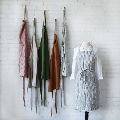 Collection of aprons hanging on a white brick wall.