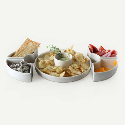 White ceramic platter with compartments filled with snacks on a white background