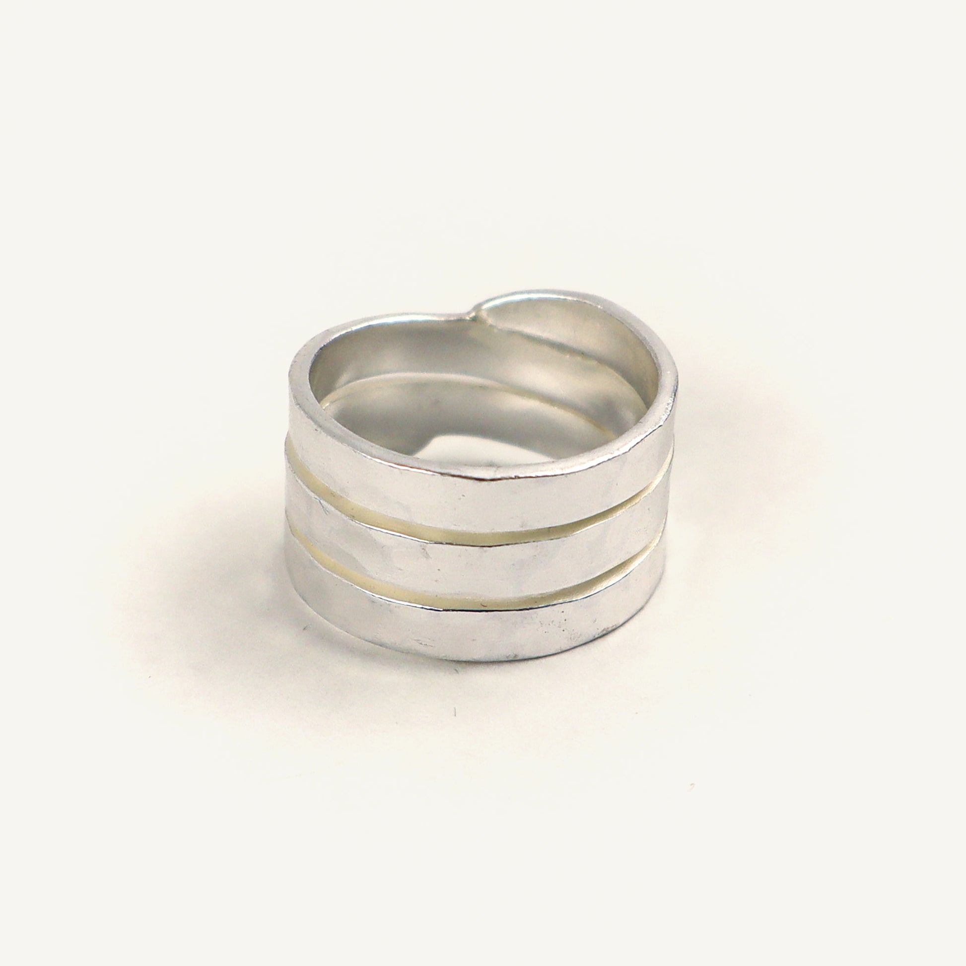 Silver ring with three horizontal bands on a light beige background